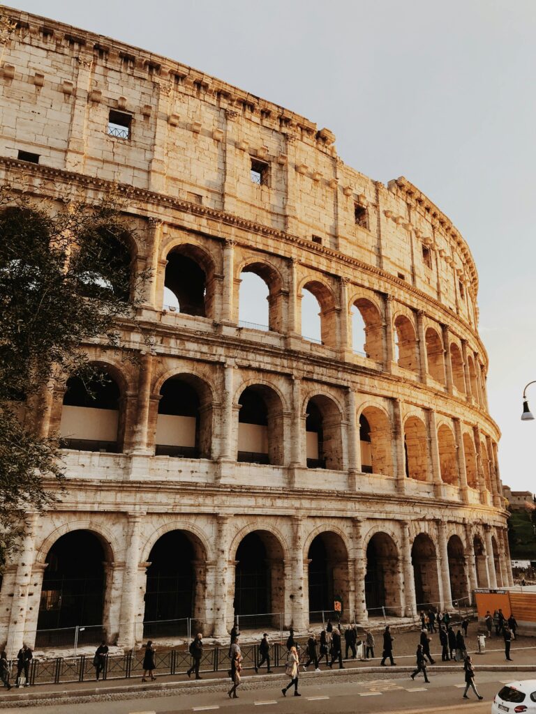 Viajes Personalizados y a Medida Iconic view of the Colosseum in Rome, Italy, at sunset with tourists outside.