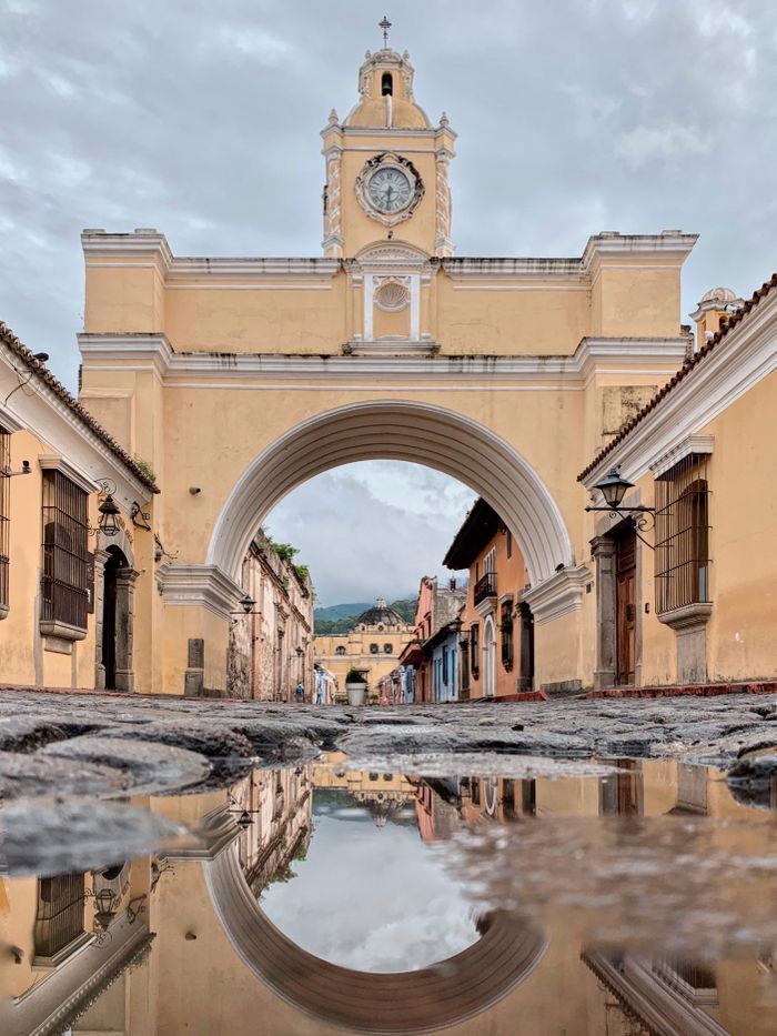 Dramatic view of the Santa Catalina Arch reflecting in a puddle after rain in Antigua, Guatemala.